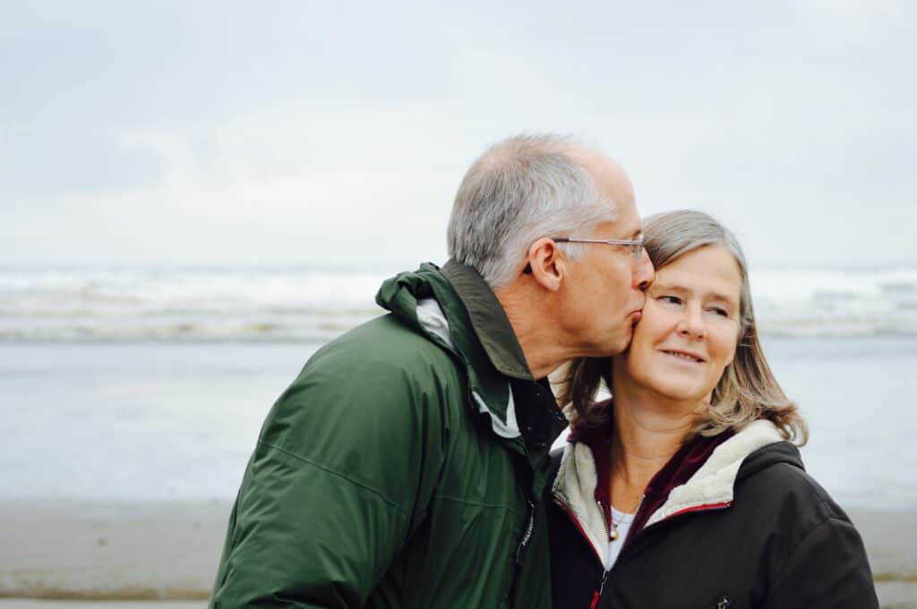 man kissing woman on check beside body of water